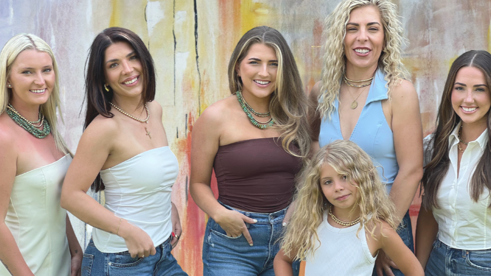 Group of women posing together in front of a colorful wall.