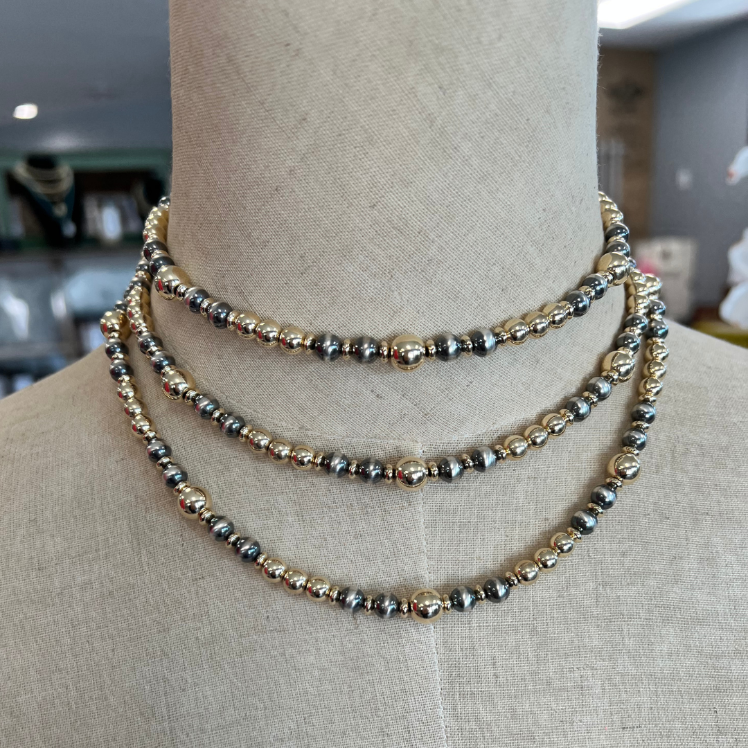 Gold and Silver Necklaces on a mannequin with a blurred indoor background