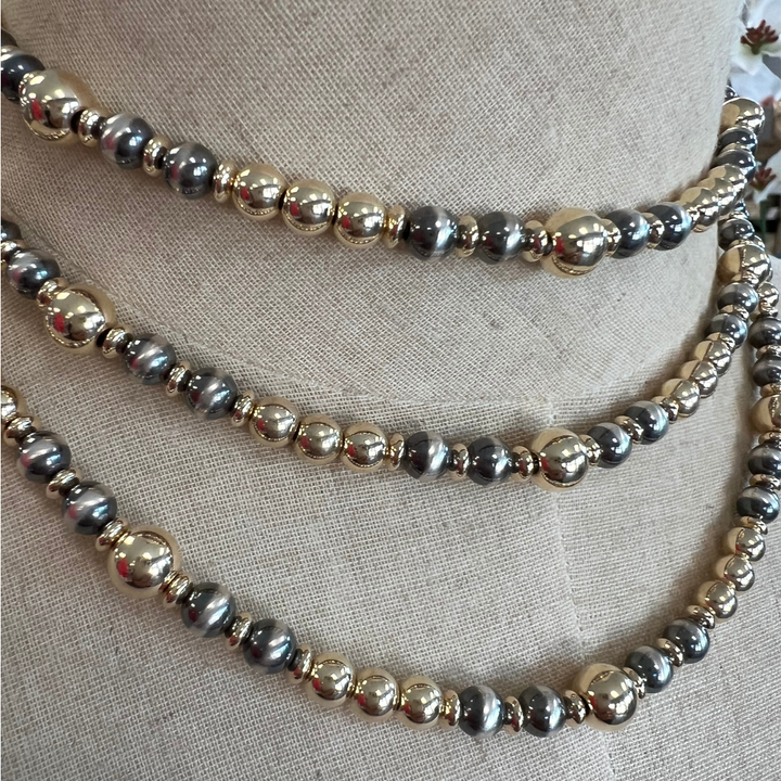 Gold and silver beaded necklaces on a textured fabric background