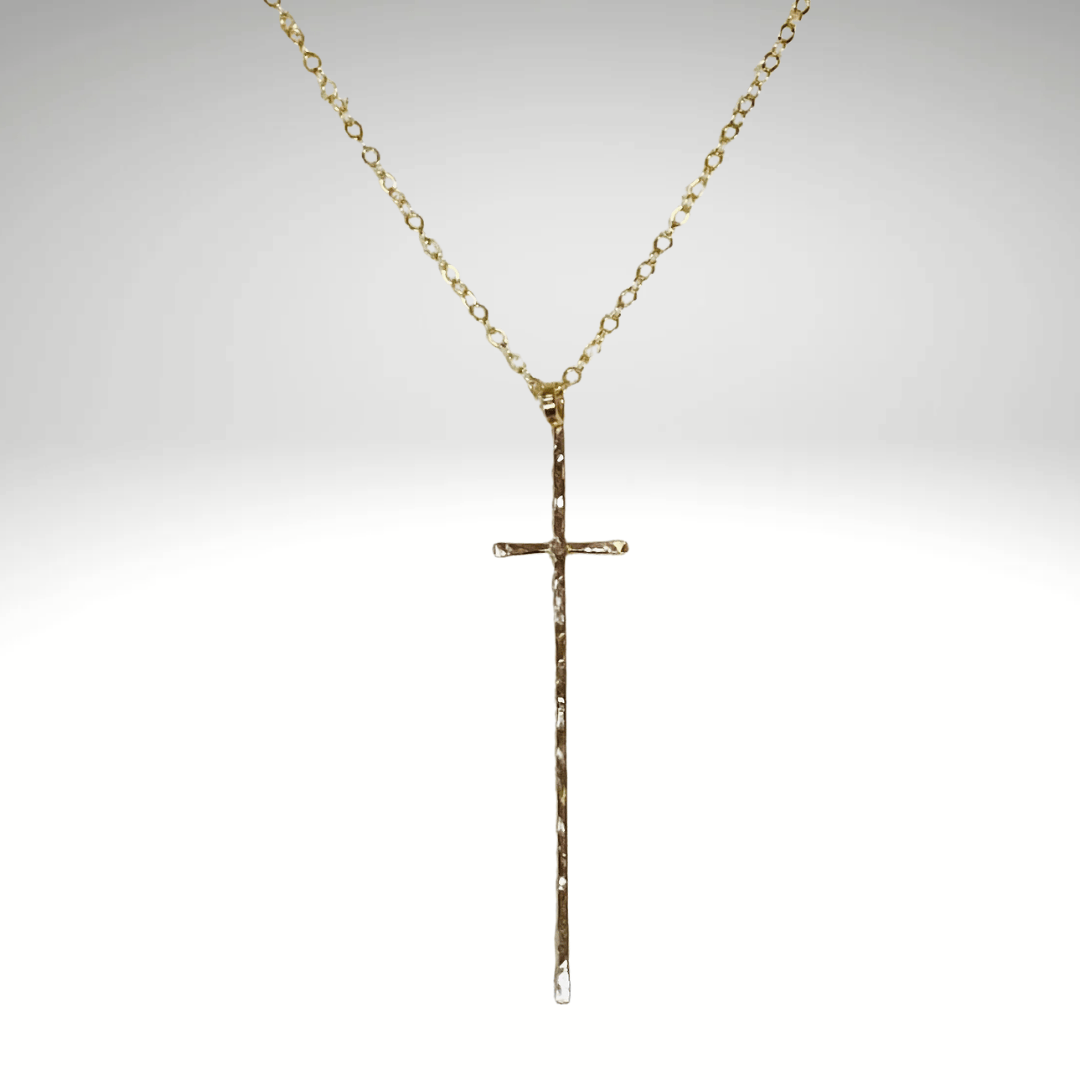 Gold cross necklace on a light gray background