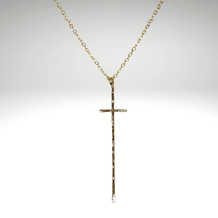 Gold cross necklace on a light gray background