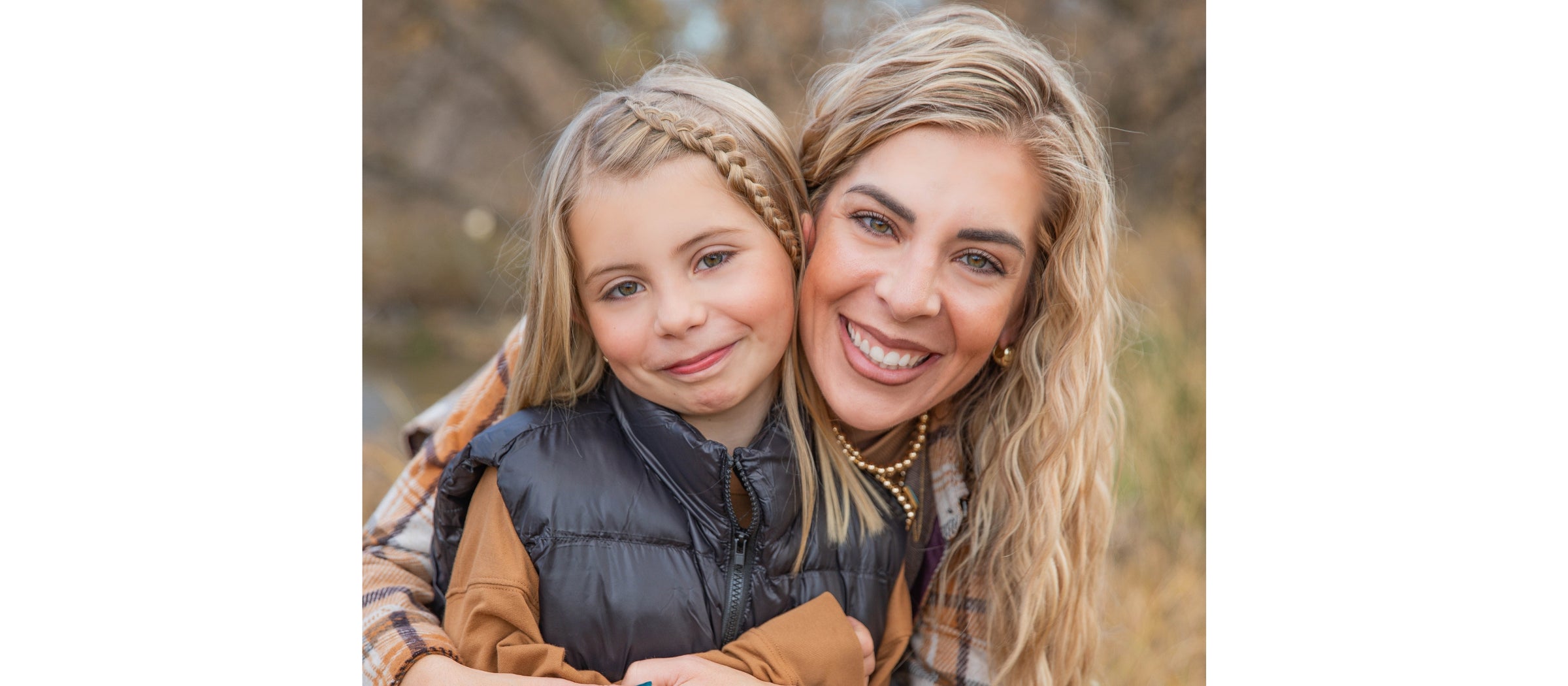 Woman and young girl hugging outdoors with a blurred natural background