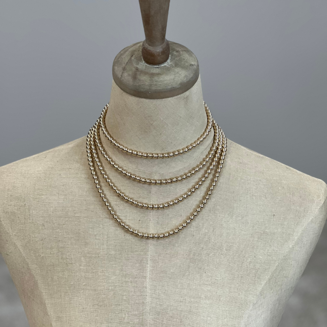 Gold Necklaces on a mannequin bust against a gray background