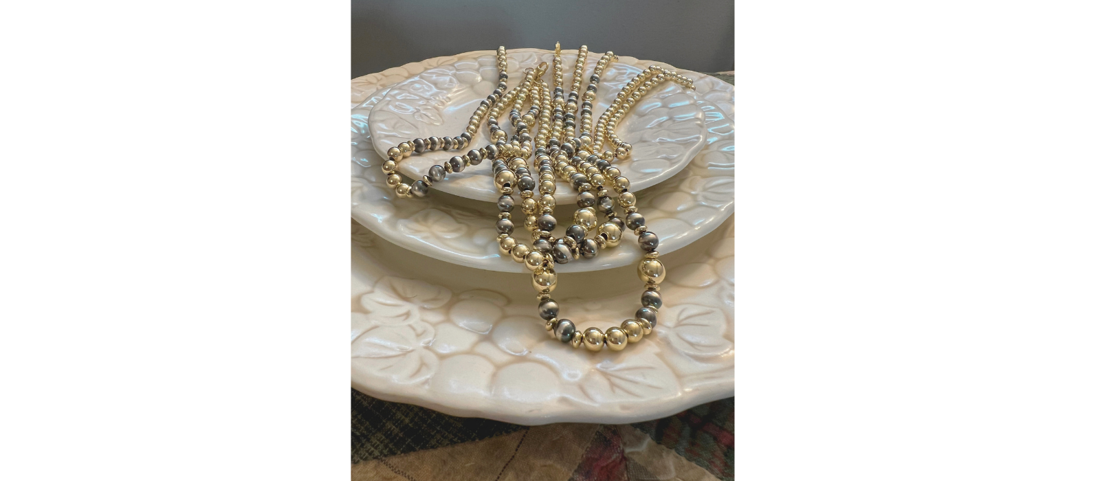 Gold and Silver Necklace on a decorative plate with a neutral background