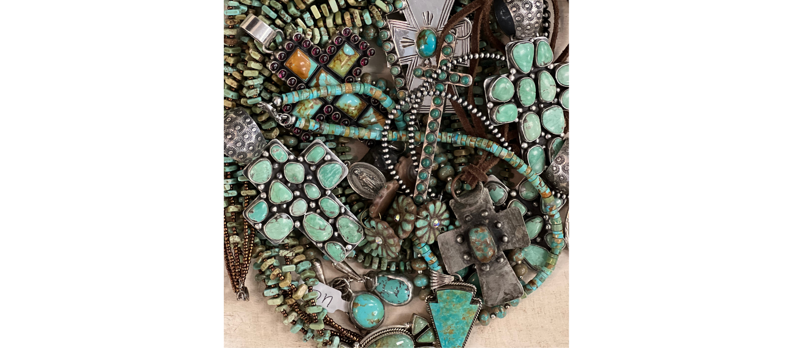Collection of turquoise and silver jewelry on a beige surface