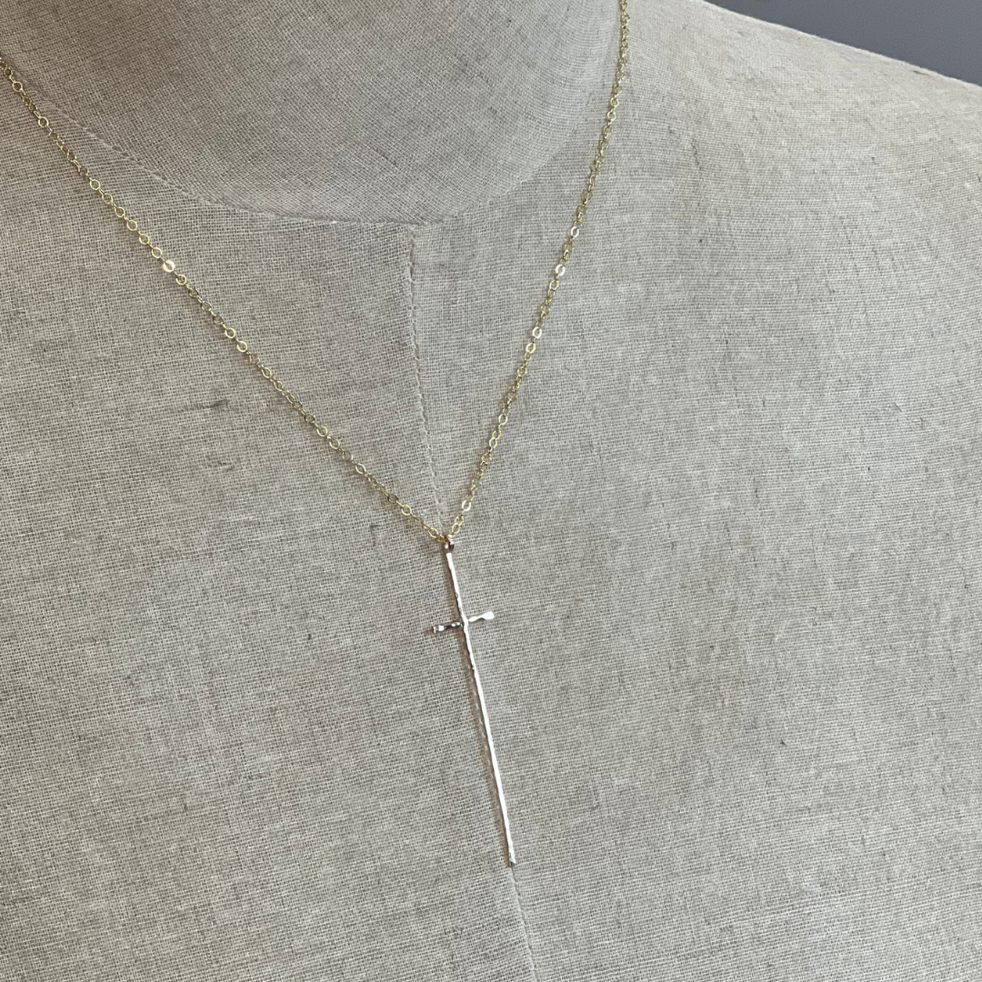 Gold necklace with a cross pendant on a gray fabric background