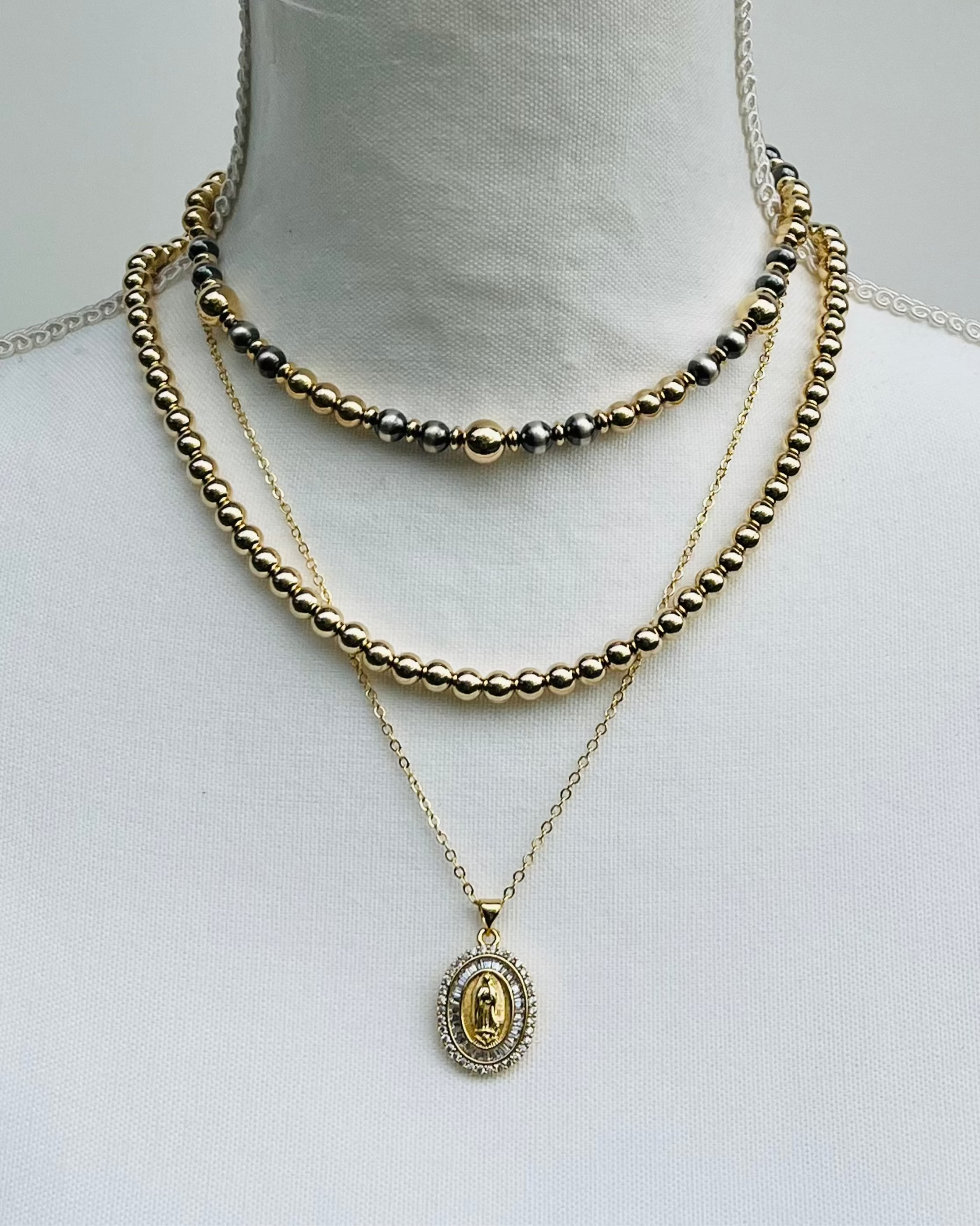 Gold Necklaces and a Christian medal on a mannequin with a plain background