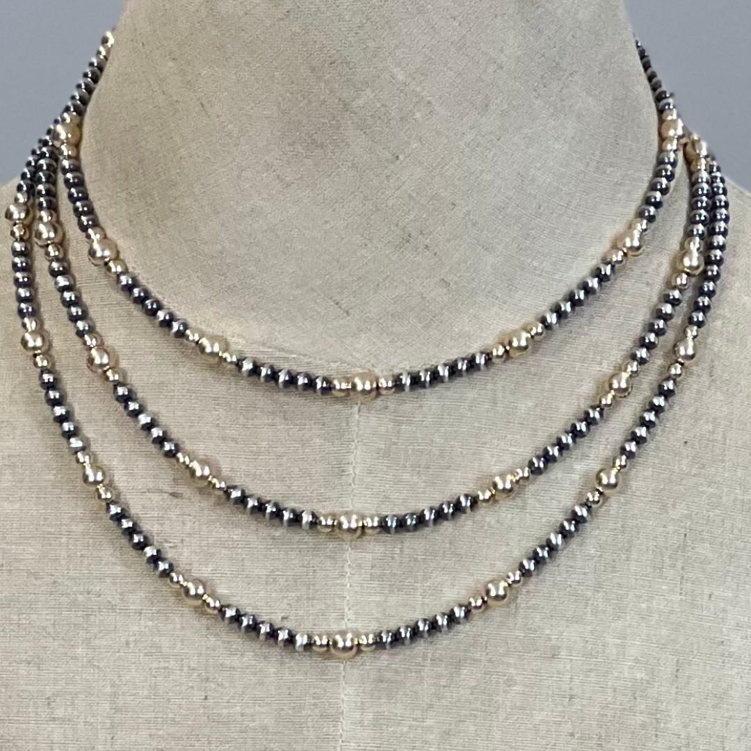 Three layered gold and silver  pearl necklaces on a mannequin bust.