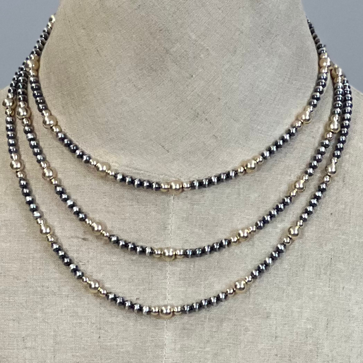 Three layered gold and silver  pearl necklaces on a mannequin bust.