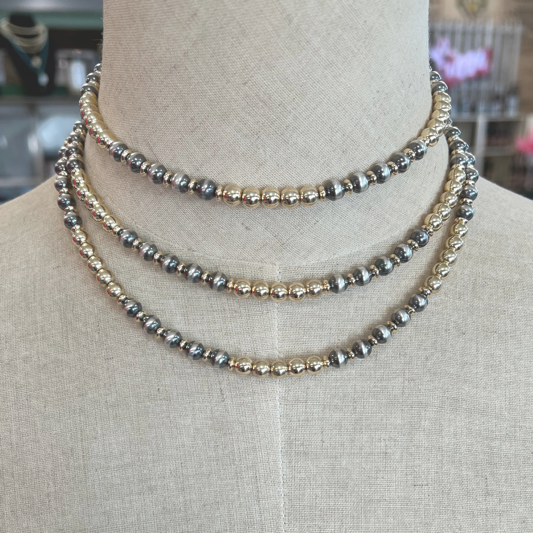 Three gold and silver beaded necklaces on a mannequin bust.