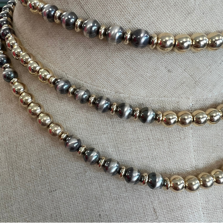 Gold and silver beaded necklaces on a textured fabric background