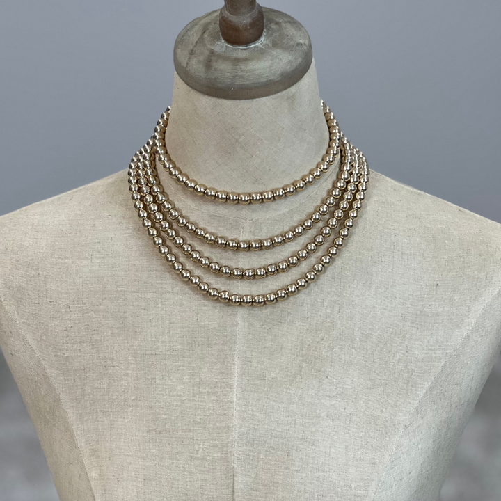 Gold Necklace on a mannequin with a plain background
