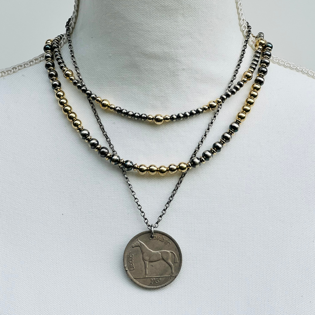 Gold and Silver Necklace with layered beads and a coin pendant on a white background