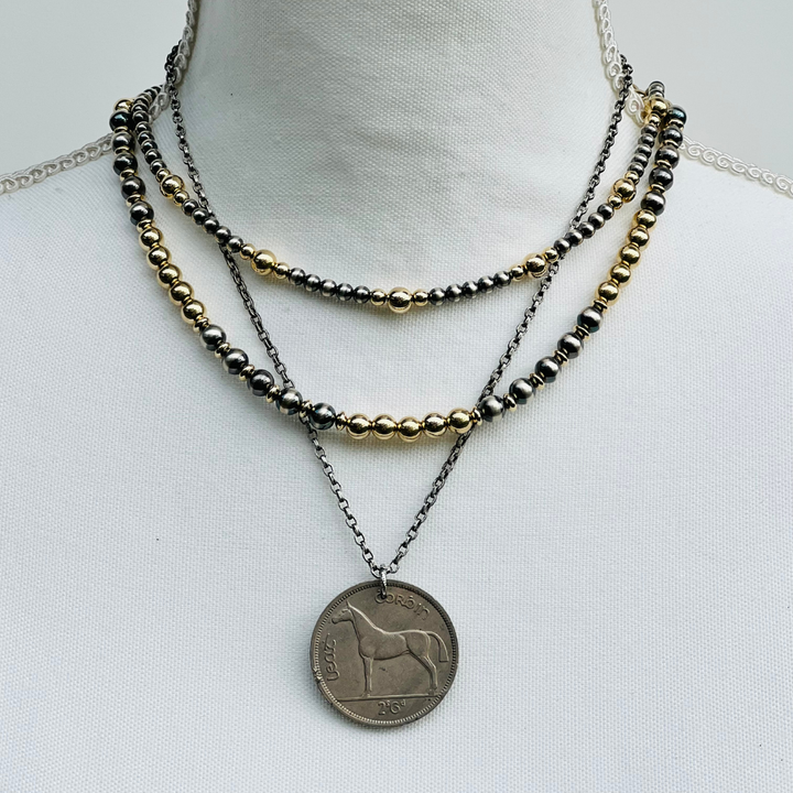 Gold and Silver Necklace with layered beads and a coin pendant on a white background